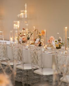 the tables are set up with white linens and clear chairs for an elegant dinner