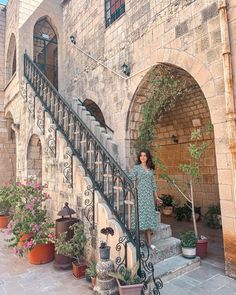 a woman standing at the top of a set of stairs next to potted plants