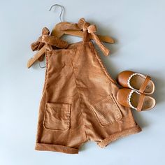 a pair of baby shoes next to a brown corded romper and slippers