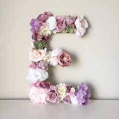 the letter e is made up of flowers on a table with a white wall in the background