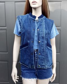 Vintage 80's denim vest with  Snap buttons down the front.  Navy blue ribbing around neck and front pockets.  Label:  Organically Grown.  .  Such a cool vest.  Has a small light whit spot on lower front. Measurements are taken with item laying flat so widths across must be doubled  Label says size small but please use measurements to see if it will work for you. Length = 23 1/2  in Across under arms =  19 1/2  in Across the bottom opening  =  18  in Please be sure to use the measurements to help Casual Medium Wash Button-up Vest, Blue Denim Vest With Button Closure, Casual Denim Blue Vest With Buttons, Casual Cotton Vest With Snap Buttons, Medium Wash Denim Vest With Buttons, Casual Denim Vest With Snap Buttons, Blue Denim Vest With Buttons, Light Wash Cotton Denim Vest With Buttons, Casual Cotton Denim Vest With Snap Buttons