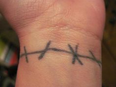 a close up of a person's wrist with a cross tattoo on the wrist