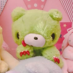 a green teddy bear sitting next to other stuffed animals