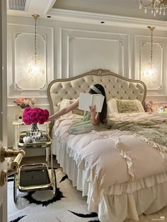 a woman laying on top of a bed with a book in her hand while reading