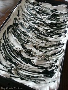 a tray filled with lots of white and black icing on top of a wooden table