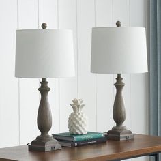 two lamps are sitting on a table with books