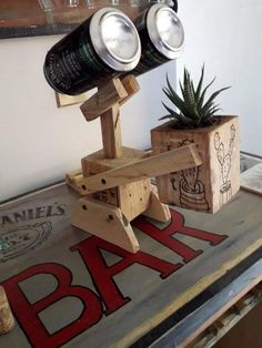 two beer bottles are sitting on top of a wooden stand with a plant in it