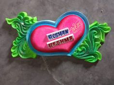 a heart shaped brooch with the name roshn on it's side