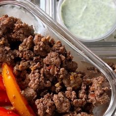 a meal in a plastic container with meat and vegetables next to some sauces on the side