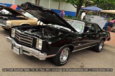 an old black car with its hood open at a car show in front of a building