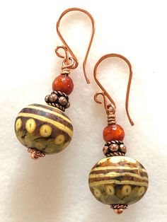 "Stunning artisan lampwork rondelle bead earrings in caramel, taupe, and coppery gold swirl design accented with rustic orange fire agates and copper beads. These gorgeous handmade large rondelle beads are 11 x 15mm with smooth matte finish. Slivers of glass and fine silver are used to \"draw\" intricate designs before beads are kiln fired at +900 degrees. The result is a beautiful unique one of a kind lampwork bead. I have matched colors and patterns as closely as possible but no two are alike. Brown Czech Glass Bead Earrings, Artisan Beaded Earrings, Artisan Czech Glass Beaded Round Earrings, Artisan Czech Glass Round Bead Earrings, Brown Copper Beaded Earrings, Artisan Orange Round Bead Earrings, Artisan Copper Beaded Earrings As Gift, Artisan Copper Beaded Earrings For Gift, Artisan Brown Beaded Nickel-free Earrings