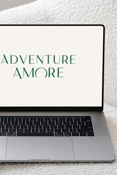 an open laptop computer sitting on top of a white blanket with the words adventure amore