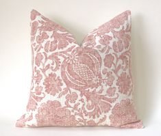 a pink and white pillow sitting on top of a white table next to a wall