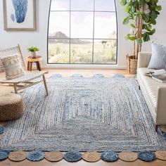 a living room filled with furniture and a large window covered in blue rugs next to a white couch