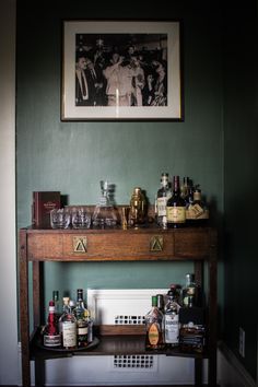 a bar with liquor bottles and glasses on it next to a framed photograph above the bar