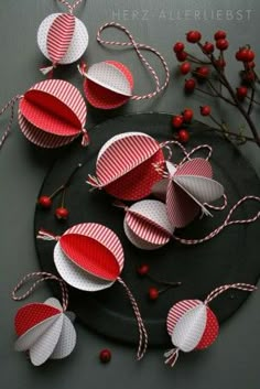 some red and white paper decorations on a black plate with berries in the corner next to it