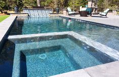 an empty swimming pool in the middle of a yard with lounge chairs and water features