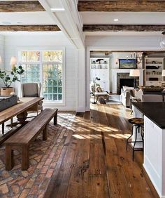 a large open concept living room with wood flooring and exposed beams in the ceiling