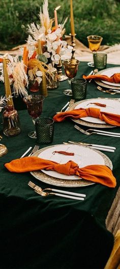 the table is set with orange napkins and place settings for an outdoor dinner party