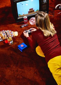 a woman sitting on the floor in front of a tv playing video games with nintendo wii controllers