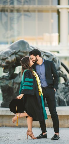 a man and woman kissing in front of a statue