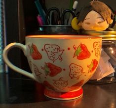 a coffee cup sitting on top of a counter next to a stuffed animal and other office supplies