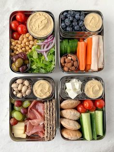 four trays filled with different types of food on top of a white countertop