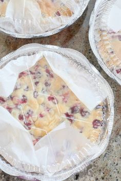 three pies sitting on top of a table covered in plastic wrap