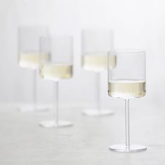 four wine glasses with white wine in them