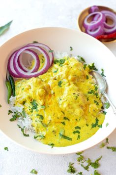 a white bowl filled with eggs and onions on top of rice next to onion slices