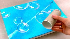 a hand holding a paper tube with soap bubbles on it