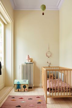 a baby's room with a crib, bed and rug on the floor