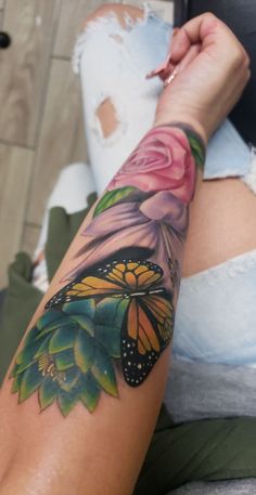 a woman's arm with a butterfly and flower tattoo on the left side of her arm