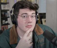 a young man wearing headphones sitting in front of a microphone