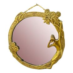 a gold mirror with a woman holding a flower in the shape of a bird on it