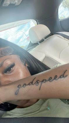 a woman is sitting in the back seat of a car and has her arm tattooed