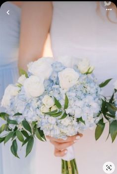 a bride holding a bouquet of white and blue flowers