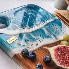 a cutting board topped with blueberries and watermelon next to an open book