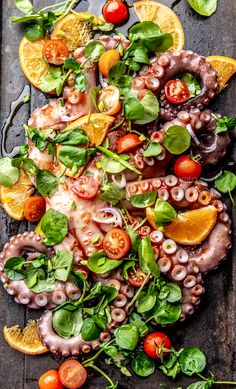 an octopus salad with tomatoes, oranges and spinach on a wooden table top