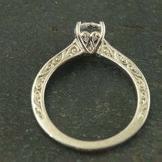 an antique style engagement ring with a heart shaped center stone in the middle and filigrees on the sides