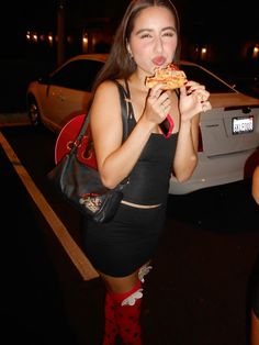 a woman eating a slice of pizza at night