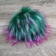 a green and purple fur ball on top of a wooden table