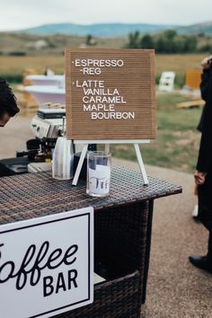 a man standing next to a table with a sign on it that says coffee bar