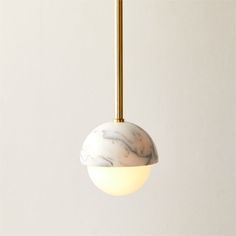 a white marble ball hanging from a brass colored light fixture with a black and white cord