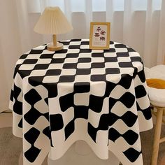 a black and white table cloth on a chair in front of a window with a lamp