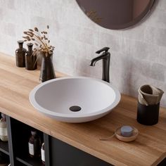 a white sink sitting on top of a wooden counter next to bottles and vases