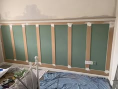 a room that has been painted with green and white stripes on the wall, along with other paint supplies