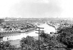 an old black and white photo of a river running through a city with lots of buildings