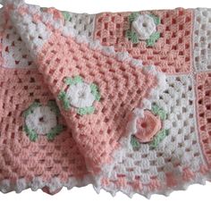 a pink and white crocheted blanket with flowers on it