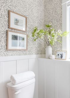 a white toilet sitting in a bathroom next to a window with pictures on the wall